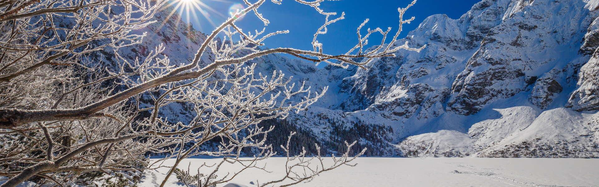 Zbocza gór pokryte warstwa śniegu. Morskie Oko zamarznięte i pokryte śniegiem.