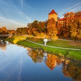 Zamek z kwadratową wieżą, stojący na wzgórzu nad rzeką. W kolorach jesieni.